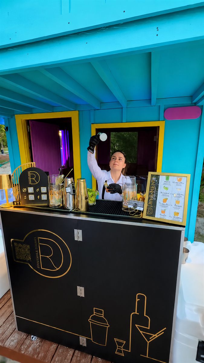Barra móvil negra con logo dorado de DR Bartender Service montada en un evento